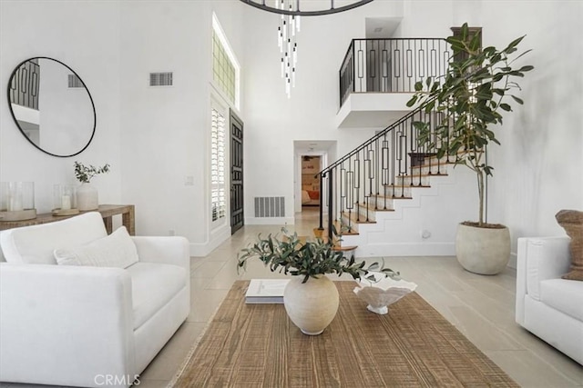 living room with baseboards, visible vents, a high ceiling, and stairs