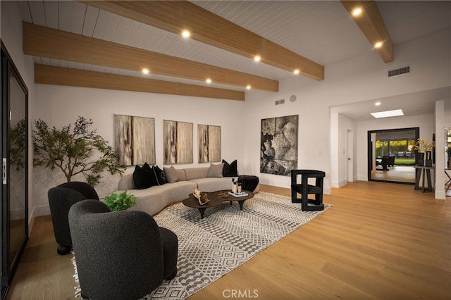 living area featuring visible vents, wood finished floors, beam ceiling, and baseboards