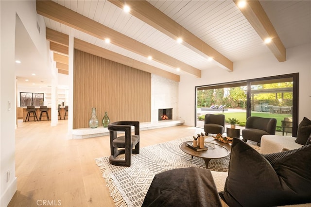 living area featuring light wood-type flooring, a fireplace, and beamed ceiling