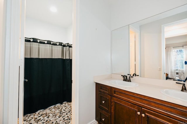 full bath with double vanity, curtained shower, and a sink