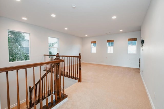 corridor featuring recessed lighting, baseboards, light colored carpet, and an upstairs landing