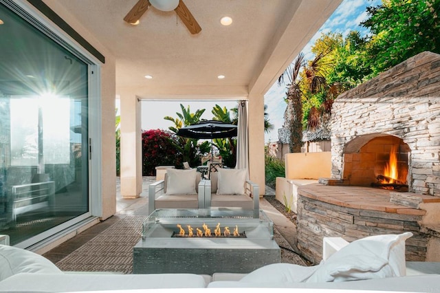 view of patio featuring ceiling fan, an outdoor living space with a fireplace, and fence