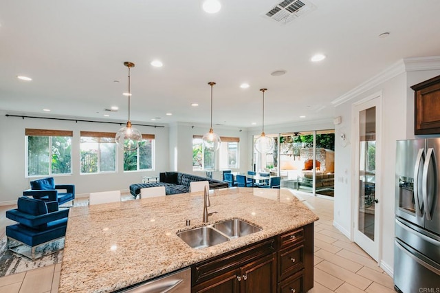 kitchen featuring stainless steel fridge, visible vents, ornamental molding, open floor plan, and a sink