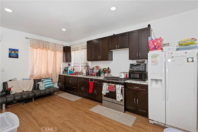 kitchen with white refrigerator with ice dispenser, light wood-style flooring, stainless steel gas stove, dark brown cabinets, and black microwave