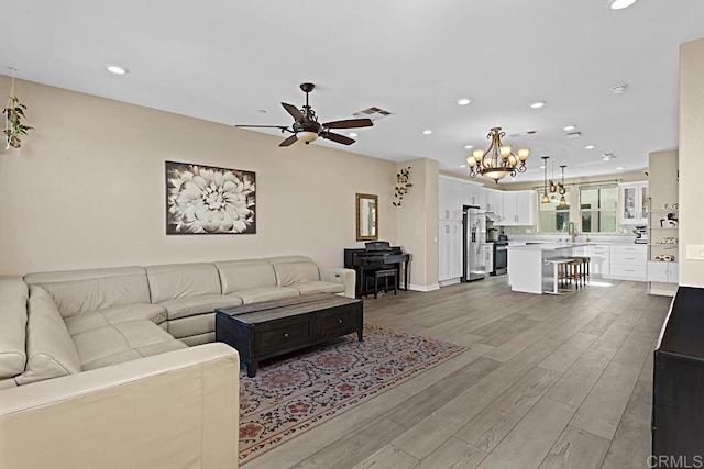 living room with recessed lighting, visible vents, wood finished floors, baseboards, and ceiling fan with notable chandelier