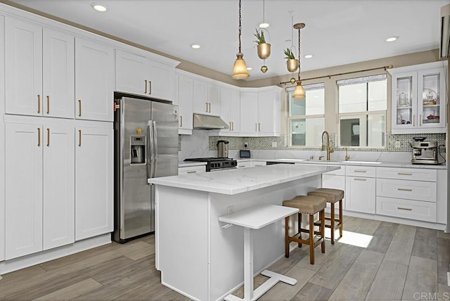 kitchen with white cabinets, range, light wood-style flooring, under cabinet range hood, and stainless steel refrigerator with ice dispenser