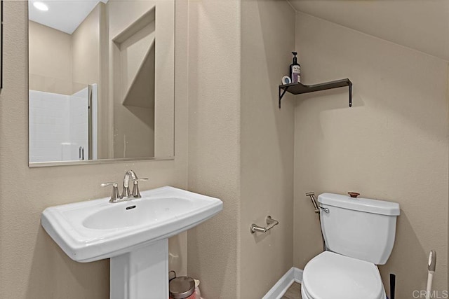 bathroom featuring toilet, baseboards, and a sink