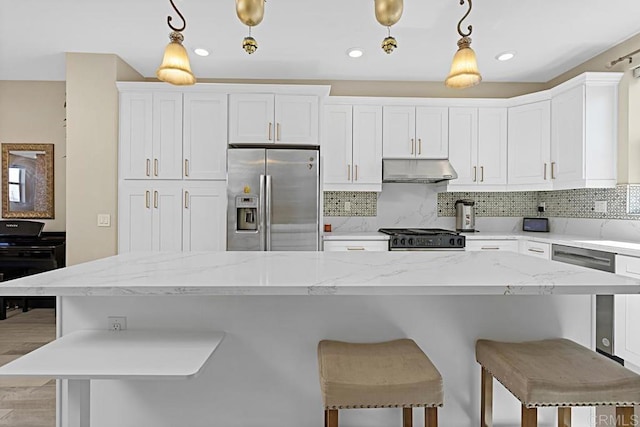 kitchen featuring stainless steel appliances, a kitchen bar, backsplash, and under cabinet range hood