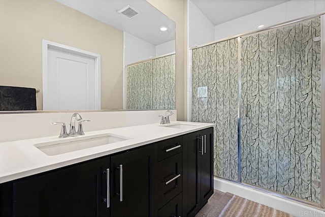 bathroom featuring double vanity, a shower stall, visible vents, and a sink