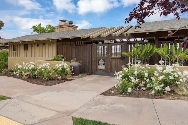 view of front of house with a chimney, a gate, fence, and board and batten siding