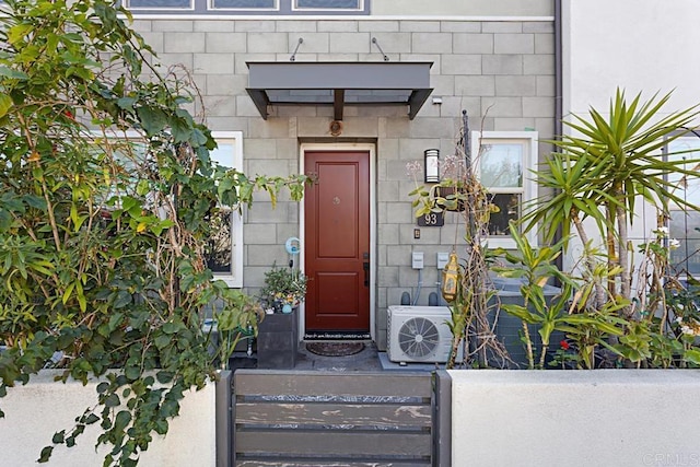 entrance to property featuring stone siding and ac unit