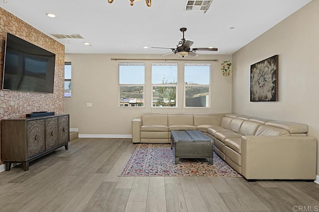 living area featuring light wood finished floors, baseboards, visible vents, and a ceiling fan