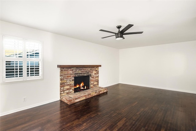 unfurnished living room featuring a ceiling fan, a brick fireplace, baseboards, and wood finished floors