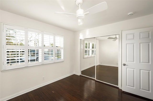 unfurnished bedroom featuring ceiling fan, a closet, baseboards, and wood finished floors