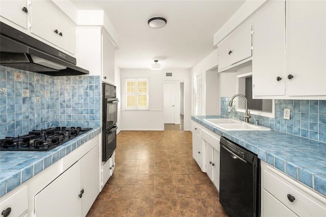 kitchen featuring tile countertops, under cabinet range hood, a sink, white cabinetry, and black appliances