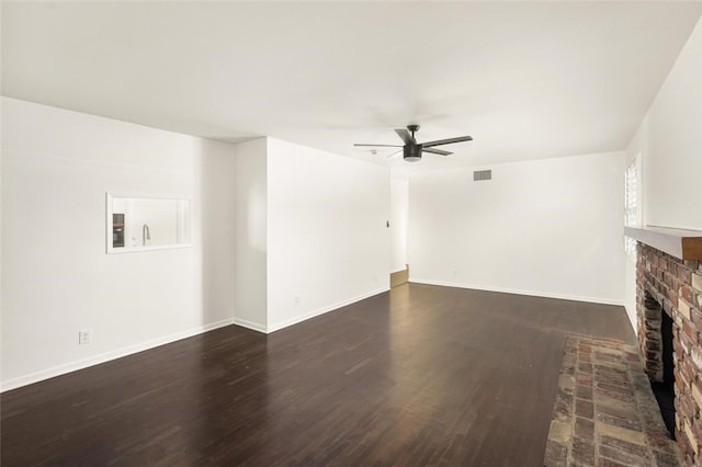 unfurnished living room featuring ceiling fan, dark wood-type flooring, a fireplace, visible vents, and baseboards