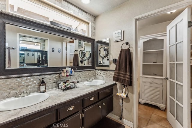 full bathroom with double vanity, backsplash, a sink, and tile patterned floors