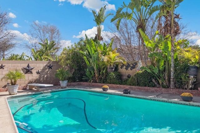 view of swimming pool with a diving board, a fenced backyard, and a fenced in pool