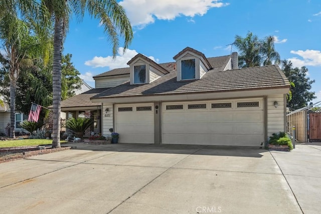 view of front of property featuring a garage, concrete driveway, and a tiled roof