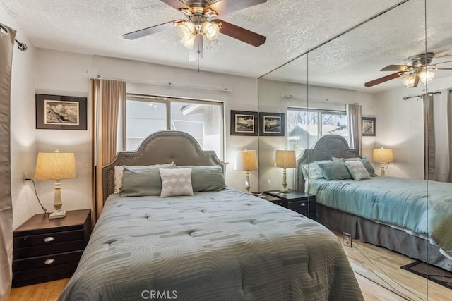 bedroom featuring ceiling fan, a textured ceiling, and wood finished floors