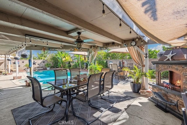 view of patio with a fenced in pool, a ceiling fan, a fenced backyard, outdoor dining area, and an outdoor stone fireplace