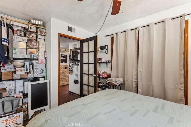 bedroom with a ceiling fan, visible vents, and a textured ceiling