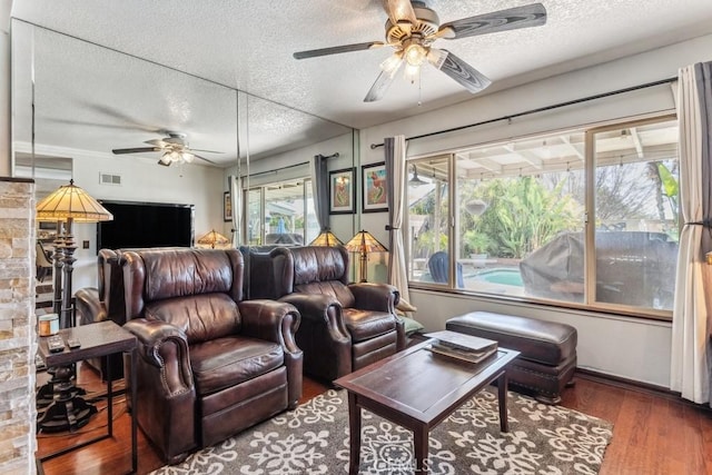 living area featuring a ceiling fan, a textured ceiling, visible vents, and wood finished floors