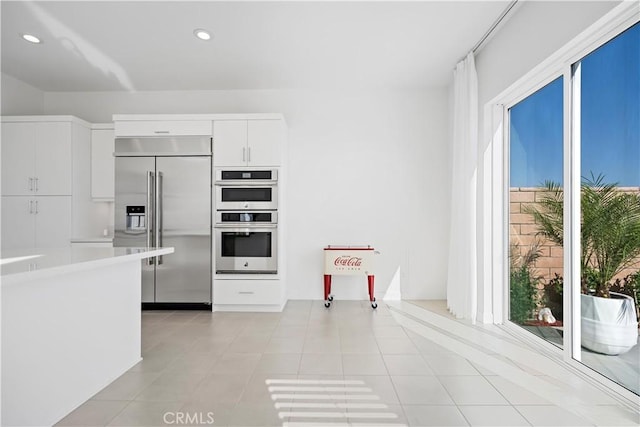 kitchen featuring light tile patterned floors, recessed lighting, white cabinetry, light countertops, and appliances with stainless steel finishes