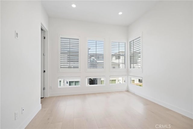 spare room featuring light wood finished floors, baseboards, and recessed lighting