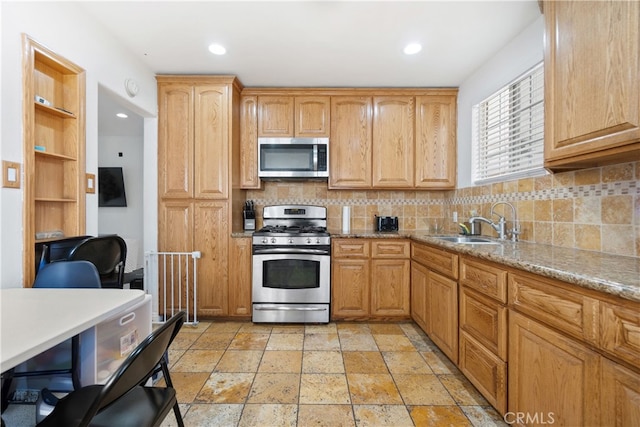 kitchen featuring appliances with stainless steel finishes, backsplash, a sink, and light stone countertops