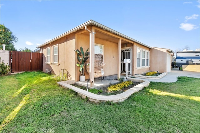 view of front of property featuring a front yard, fence, a patio, and stucco siding