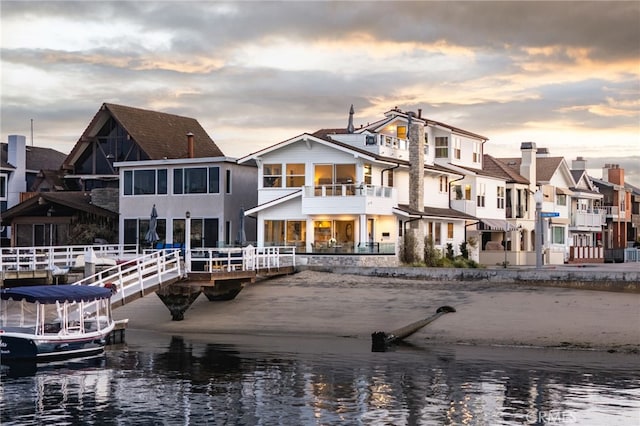 back of house at dusk with a residential view and a water view