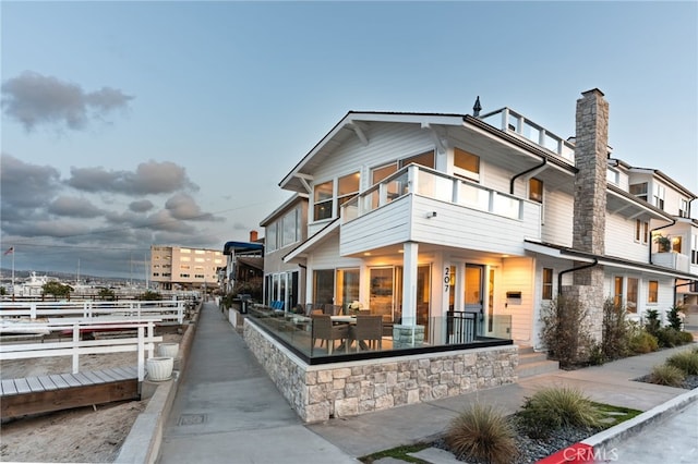 207 E Edgewater Ave Unit A, Newport Beach, CA 92661 - back of property with stone siding, a chimney, and a balcony