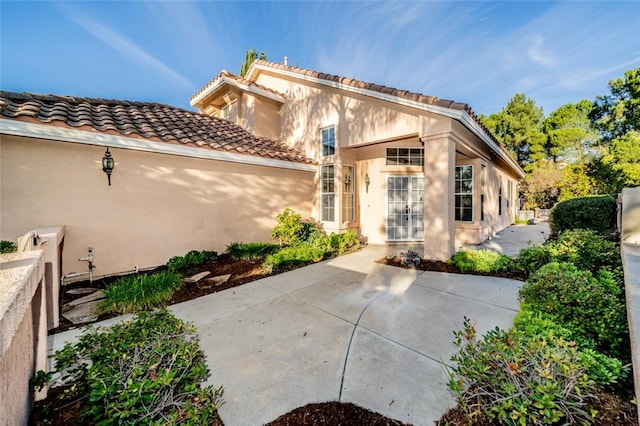 back of house with a patio area, a tile roof, and stucco siding