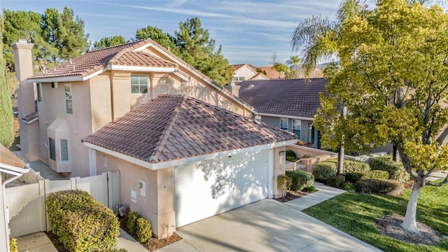 view of front of house featuring driveway, a tile roof, an attached garage, fence, and stucco siding