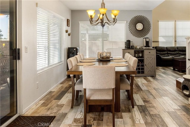 dining room with light wood-style floors, baseboards, and an inviting chandelier