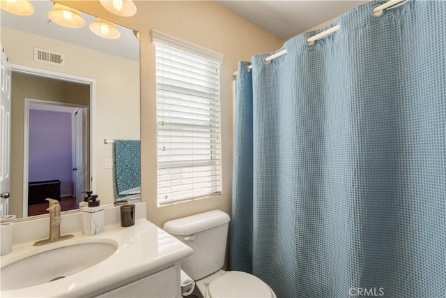 bathroom featuring toilet, a shower with curtain, visible vents, and vanity