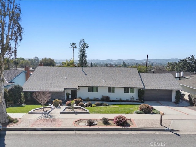 view of front of home with an attached garage, a front lawn, and concrete driveway