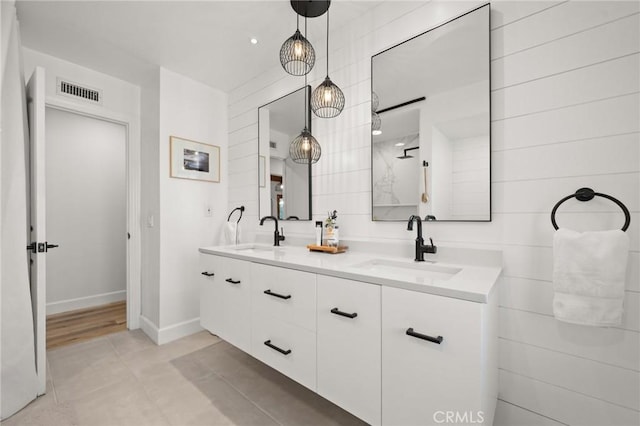 full bathroom featuring double vanity, baseboards, visible vents, and a sink