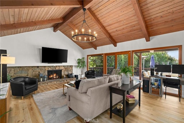 living area featuring beamed ceiling, plenty of natural light, a stone fireplace, and light wood finished floors