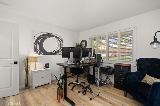 home office with light wood-style flooring and baseboards