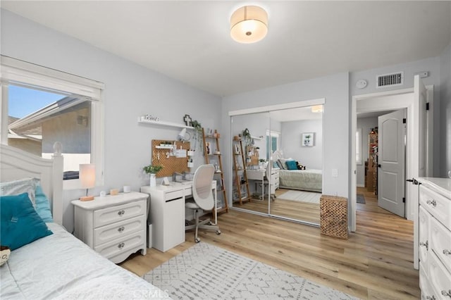 bedroom featuring a closet, visible vents, and light wood finished floors