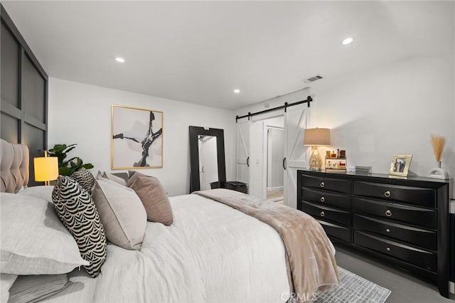 bedroom with a barn door, visible vents, and recessed lighting