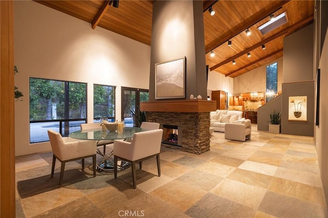 interior space with wooden ceiling, high vaulted ceiling, and a stone fireplace