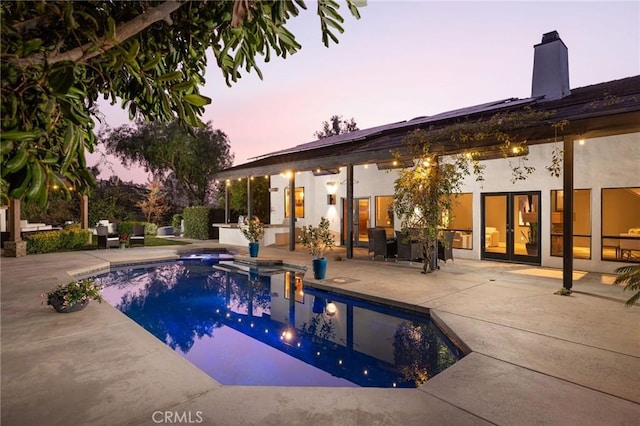 pool at dusk with a patio and an outdoor pool