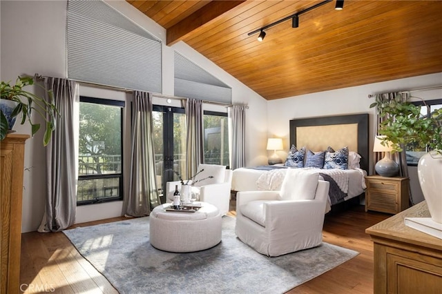 bedroom with multiple windows, wooden ceiling, vaulted ceiling with beams, and wood finished floors