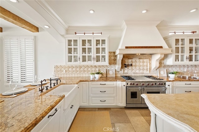 kitchen featuring white cabinets, custom exhaust hood, backsplash, and range with two ovens