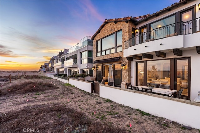 back of house at dusk featuring a residential view and stucco siding