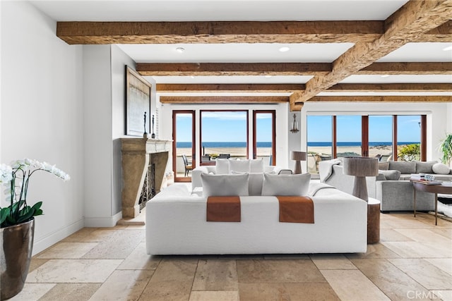 living room with stone tile flooring, a fireplace, baseboards, and beam ceiling