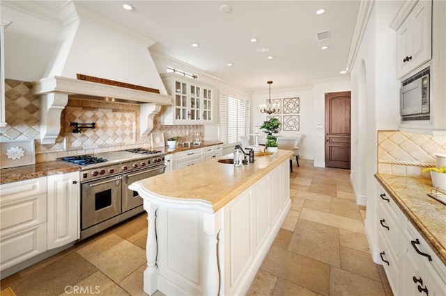 kitchen with stone tile floors, visible vents, ornamental molding, built in microwave, and double oven range